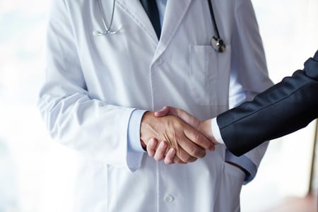 doctor handshake with a patient at doctors bright modern office in hospital-1